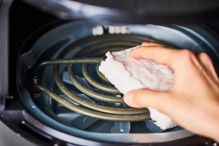 Vệ sinh khay chiên, giỏ chiên và các góc khuất thường xuyên giúp hạn chế cặn thức ăn tích tụ trong thiết bị.