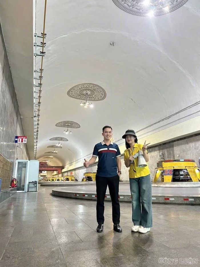 Chị Lê Thị Thanh Hằng - hướng dẫn viên tại điểm khu vực nhà máy Thuỷ điện Hoà Bình (bên phải) cùng du khách lưu lại hình ảnh trong gian máy, phía sau là dãy tổ máy đặt sâu trong lòng núi