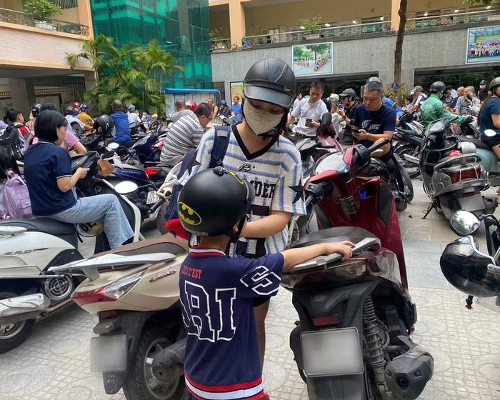Phụ huynh chủ động đội mũ bảo hiểm cho con trước khi bắt đầu lưu thông trên đường. Ảnh: Kim Tuyến