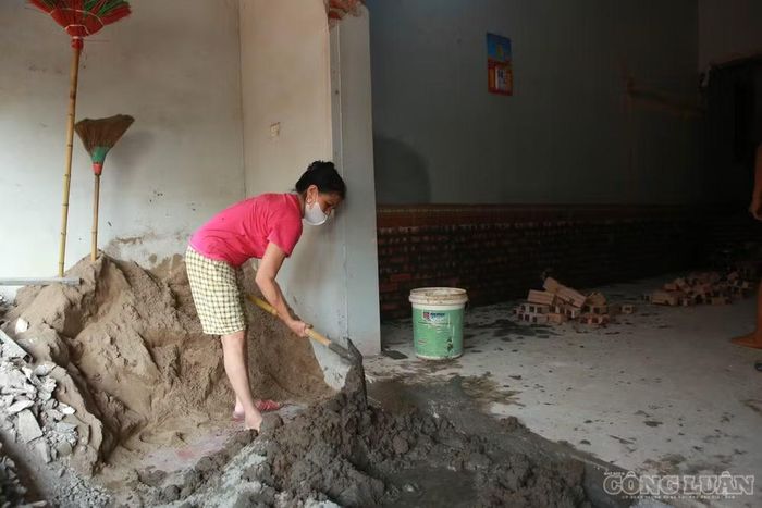 Bà Nguyễn Thị Chỉ đang cùng thợ sửa và nâng nền nhà.