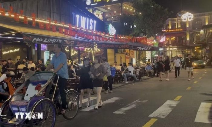 Khách du lịch buộc phải đi xuống lòng đường do vỉa hè bị các cửa hàng chiếm dụng. (Ảnh: Văn Dũng/TTXVN)