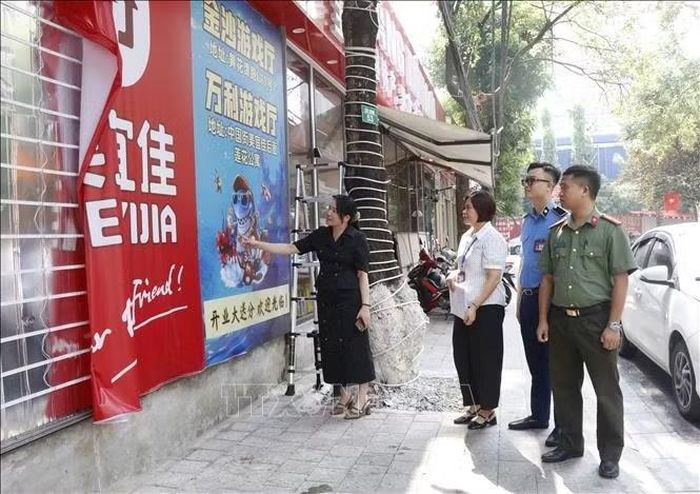 Bà Nguyễn Thị Hiền, Phó Chủ tịch UBND phường Kinh Bắc (ngoài cùng bên trái) kiểm tra và yêu cầu tháo dỡ những biển hiệu chưa phù hợp. Ảnh: Thái Hùng/TTXVN