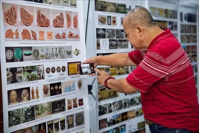 Đại biểu lưu lại những hình ảnh hiện vật và tư liệu nghiên cứu khảo cổ học được giới thiệu tại Hội thảo. Ảnh: Phạm Tuấn Anh/TTXVN