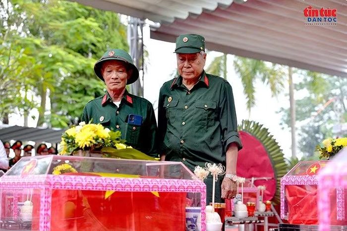 Cựu chiến binh Phạm Văn Thành (bên phải) và ông Trần Văn Tiến đứng lặng trước linh cữu các đồng đội đã nằm lại chiến trường Vị Xuyên.