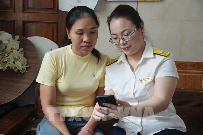 Để hỗ trợ người dân nắm chính sách, Thuế cơ sở 9 (Thuế tỉnh Nghệ An) cử cán bộ hướng dẫn người dân kê khai thuế, cài đặt và sử dụng ứng dụng eTax Mobile. Ảnh: Bích Huệ - TTXVN