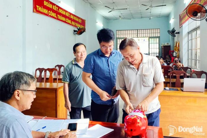 Đảng viên phường Dầu Giây đóng góp quỹ nuôi heo đất để giúp đỡ học sinh có hoàn cảnh khó khăn. Ảnh: C.T.V