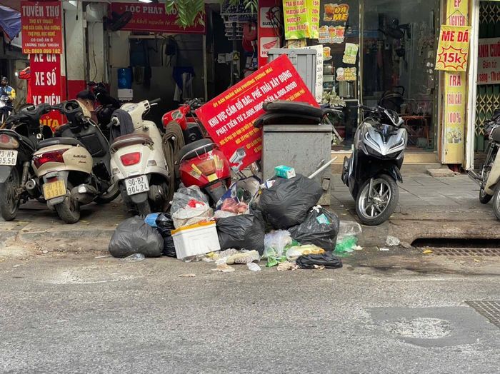 Biển cảnh báo phạt tiền của UBND phường Tương Mai bị xô lệch ngay trên đống rác. Ảnh: Hiểu Lam