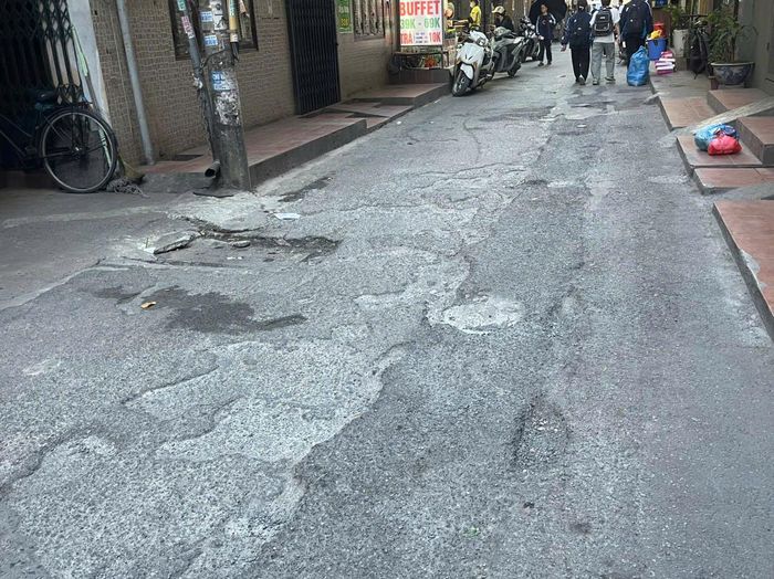 Cận cảnh mặt đường ngõ 130 Xuân Thủy gồ ghề, chắp vá. Ảnh: Lam Lam
