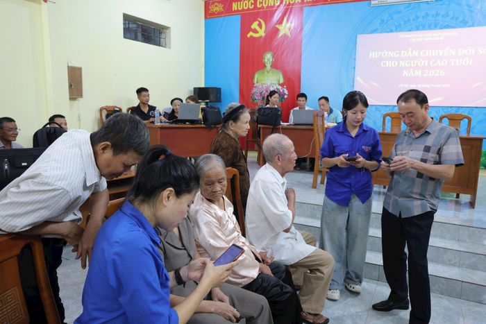 Đoàn viên thanh niên xã Phú Nghĩa hỗ trợ người cao tuổi thôn Chi Nê sử dụng ứng dụng công nghệ số trên điện thoại thông minh. Ảnh: Kim Thoa