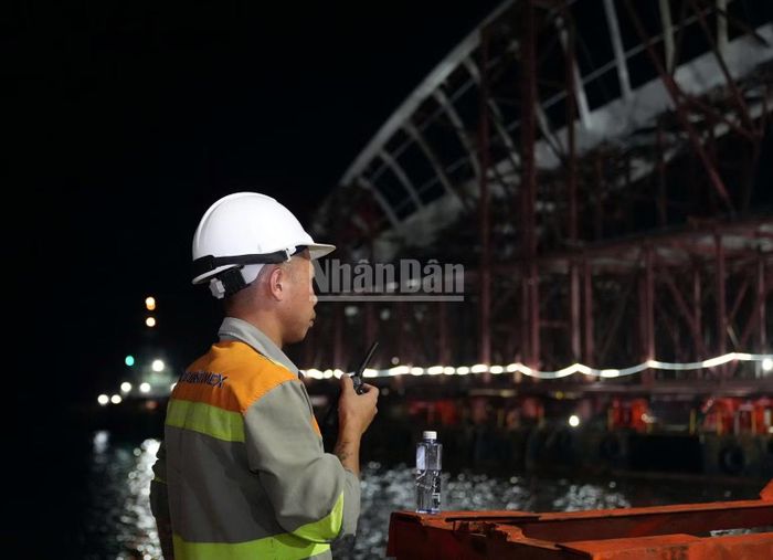 Quan sát, liên lạc để phối hợp đưa vòm thép lên sà lan. (Ảnh: Lê Đình Thìn)