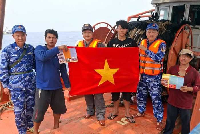 Cảnh sát biển tặng cờ Tổ quốc cho ngư dân trên biển. (Ảnh: Cảnh sát biển cung cấp)
