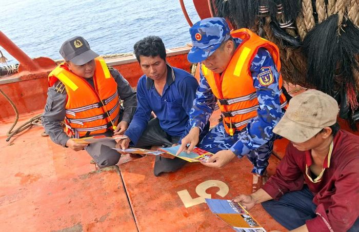 Cảnh sát biển phát tờ rơi tuyên truyền chống IUU cho ngư dân. (Ảnh: Cảnh sát biển cung cấp)