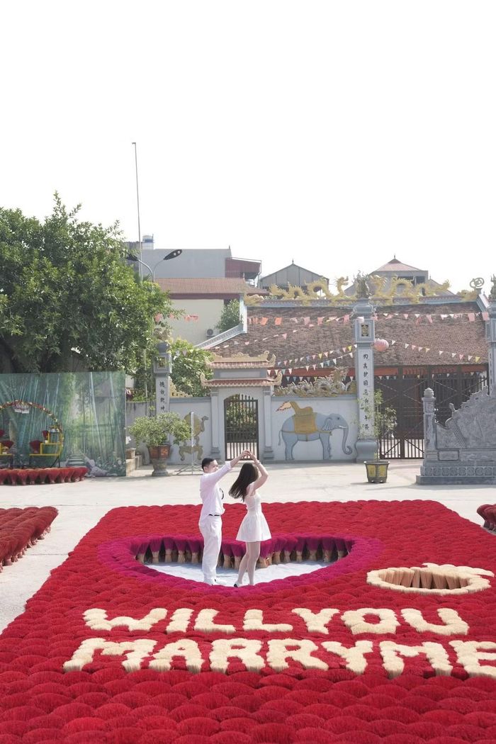 Cặp đôi có những khoảnh khắc vui vẻ ngay giữa khu vực được chuẩn bị riêng cho màn cầu hôn. Dòng chữ “Will you marry me?” được tạo bằng tăm hương màu trắng ngà nổi bật trên nền đỏ.
