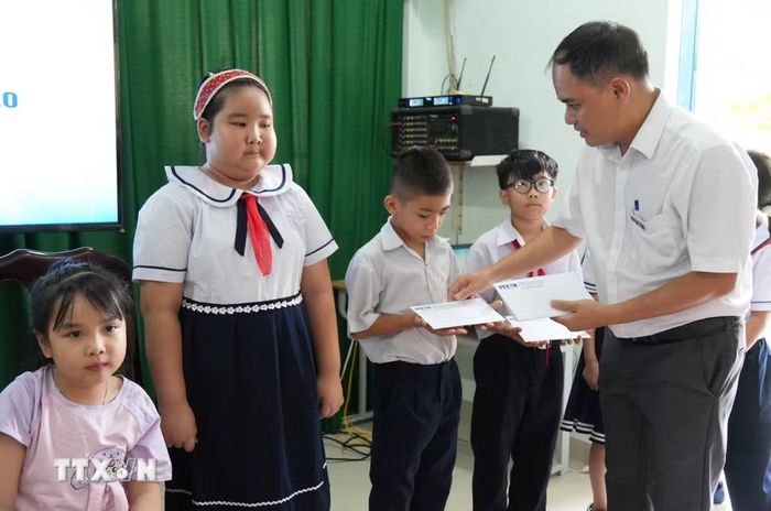 Trưởng Cơ quan thường trú TTXVN tại Khánh Hòa Vũ Xuân Triệu tặng học bổng cho học sinh có hoàn cảnh khó khăn của trường Tiểu học Tây Nha Trang. (Ảnh: Nguyễn Dũng/TTXVN)
