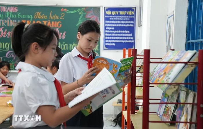 Học sinh trường Tiểu học Tây Nha Trang chọn sách tham khảo trong tủ sách Đinh Hữu Dư. (Ảnh: Nguyễn Dũng/TTXVN)