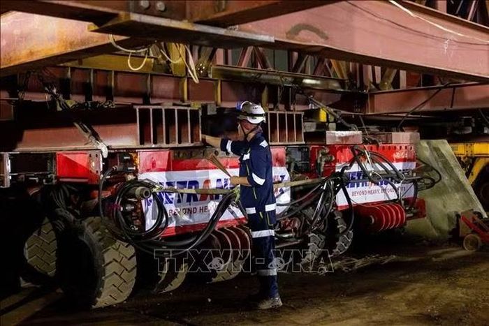Công nhân kiểm tra hệ thống thiết bị vận tải hạng nặng chuyên dụng SPMT di chuyển tổ hợp nhịp cầu lên sà lan. Ảnh: TTXVN phát