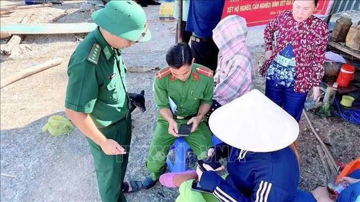 Chiến sĩ Biên phòng Hòn Chuối phối hợp cùng lực lượng Công an trực tiếp hỗ trợ hộ dân thực hiện các đăng ký tài khoản định danh điện tử. Ảnh: Văn Quơn/TTXVN phát