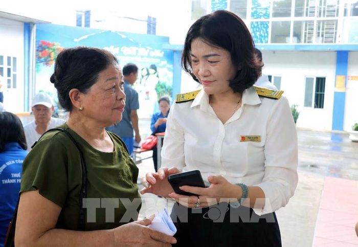 Cán bộ thuế cơ sở 3, Thuế thành phố Hải Phòng hỗ trợ người dân sử dụng ứng dụng eTax Mobile và nộp thuế sử dụng đất phi nông nghiệp. Ảnh: Hoàng Ngọc - TTXVN 
