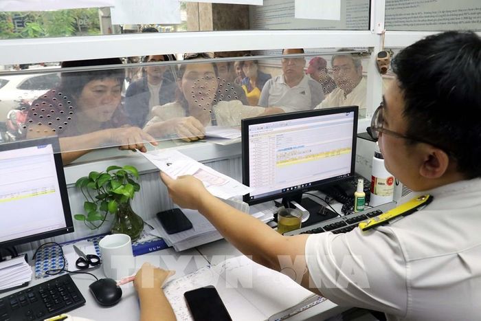 Cán bộ thuế cơ sở 3, Thuế thành phố Hải Phòng hỗ trợ người dân sử dụng ứng dụng eTax Mobile và nộp thuế sử dụng đất phi nông nghiệp. Ảnh: Hoàng Ngọc - TTXVN 