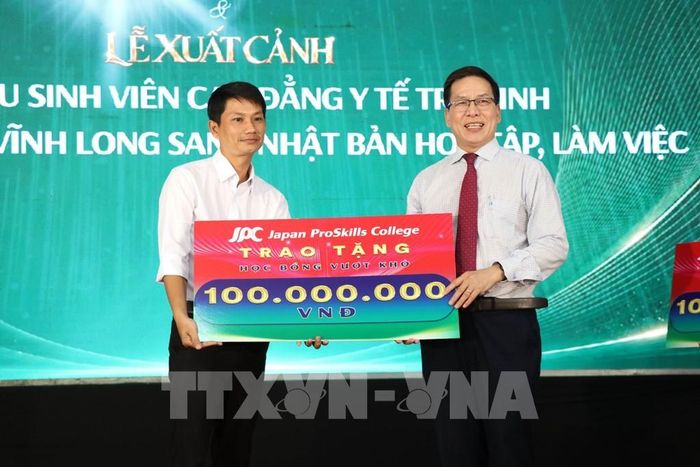 Trường Trung cấp Kỹ năng Chuyên nghiệp Nhật Bản JPC (bên phải) trao Bảng tượng trưng tặng học bổng cho học sinh vượt khó học giỏi Trường Trung học cơ sở và Trung học Phổ thông Nguyễn Văn Hai, tỉnh Vĩnh Long tại buổi lế. Ảnh: Thanh Hòa- TTXVN