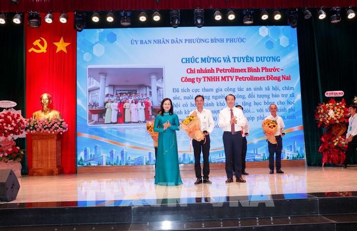 Đại diện Chi nhánh Petrolimex Bình Phước - Công ty TNHH MTV Petrolimex Đồng Nai nhận hoa chúc mừng, ghi nhận những đóng góp trong công tác an sinh xã hội tại địa phương. Ảnh: Đậu Tất Thành - TTXVN