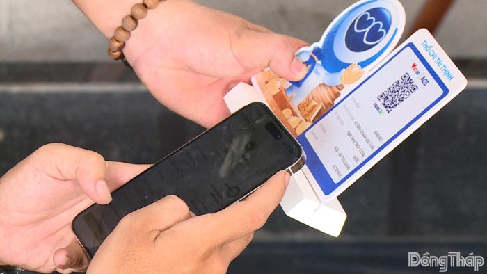 Người dân sử dụng điện thoại thông minh quét mã QR để thực hiện thanh toán không dùng tiền mặt.