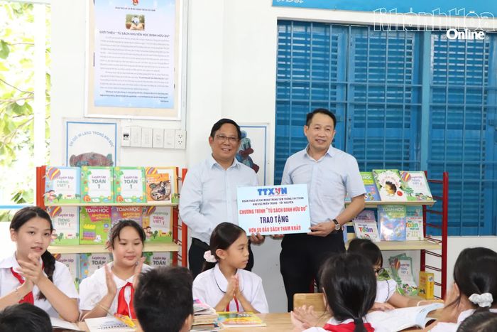 Đại diện Trung tâm Thông tin Thông tấn xã Việt Nam khu vực miền Trung - Tây nguyên (bên phải) trao bảng tượng trưng 50 đầu sách cho lãnh đạo Trường Tiểu học Tây Nha Trang.