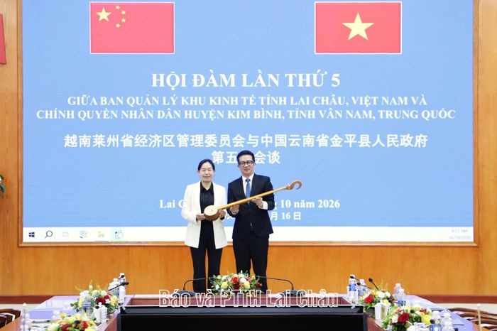 Đồng chí Vũ Huy Hòa - Trưởng Ban Quản lý Khu kinh tế tỉnh, Trưởng cửa khẩu quốc tế Ma Lù Thàng tặng chiếc đàn tính tẩu của dân tộc Thái cho đồng chí Điền Hồng Mai - Phó Bí thư Huyện ủy, Huyện trưởng Chính quyền Nhân dân huyện Kim Bình. 