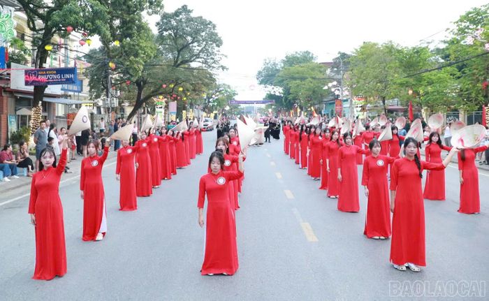 Các diễn viên trong tà áo dài đỏ, đại diện cho dân tộc Kinh, trình diễn trên đường phố Mường Lò.