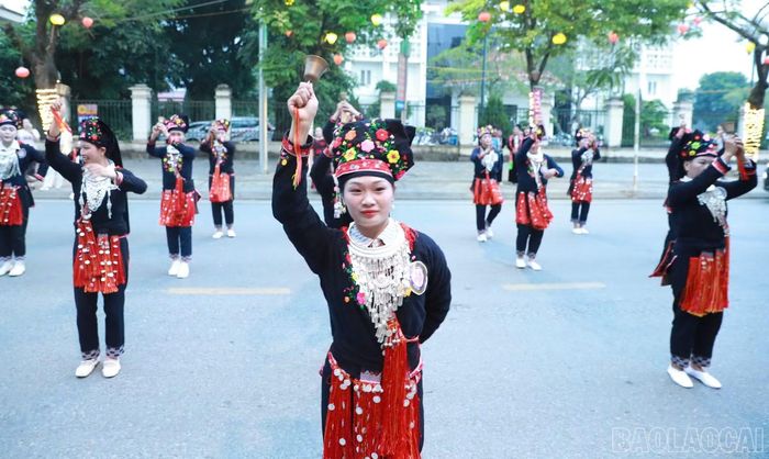 Các diễn viên dân tộc tươi tắn trong trang phục truyền thống, nhịp nhàng trình diễn điệu múa chuông trên đường phố Mường Lò.