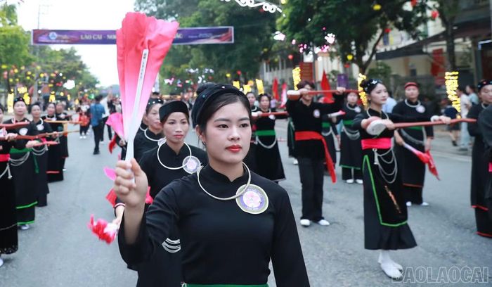 Các thiếu nữ dân tộc Tày duyên dáng trong trang phục truyền thống, trình diễn với đàn tính và quạt hồng trên đường phố Mường Lò.