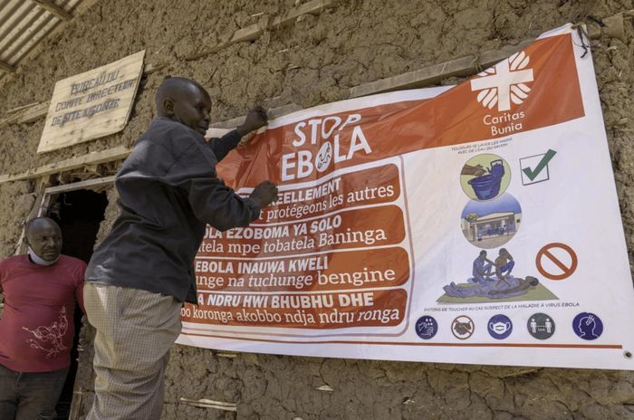 Một người đàn ông treo băng rôn tuyên truyền phòng chống Ebola tại trại Kigonze ở Bunia, miền đông Cộng hòa Dân chủ Congo. Ảnh: TNS