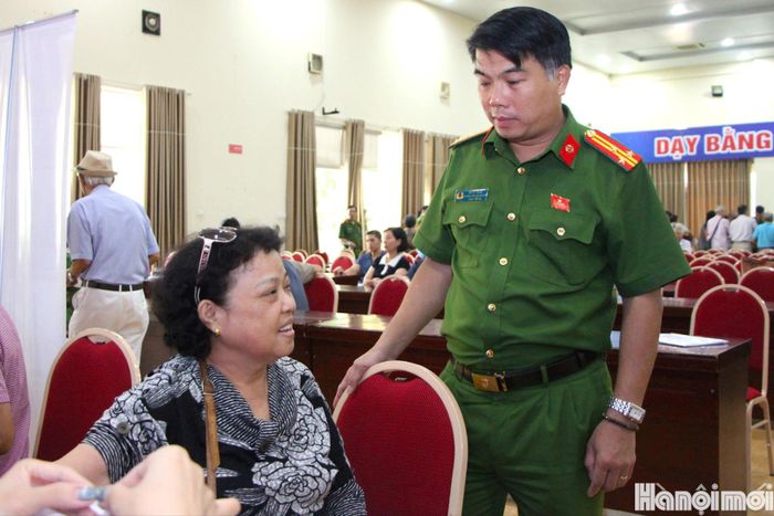 Thượng tá Đỗ Sỹ Dũng, Trưởng Công an phường Giảng Võ thăm hỏi thân nhân liệt sĩ trong quá trình lấy mẫu sinh phẩm ADN. Ảnh: MH