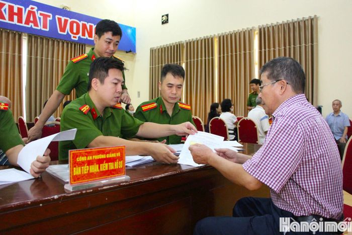 Công an phường Giảng Võ tiếp nhận, kiểm tra hồ sơ thân nhân liệt sĩ. Ảnh: MH