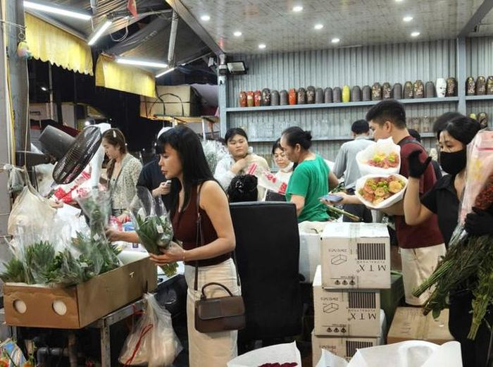 Nhiều khách hàng lựa chọn hoa tại các quầy hàng ở chợ Quảng An trong đêm trước ngày 20/10.