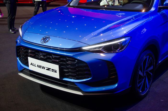  Cụm lưới tản nhiệt của MG ZS nay to hơn, mở rộng về 2 bên, kết hợp 2 khe hút gió đặt dọc tạo hình móc câu thành một diện mạo khá ấn tượng. Logo thương hiệu không còn nằm bên trong mặt ca-lăng, thay vào đó được bố trí ngay cạnh dưới của nắp ca-pô. 