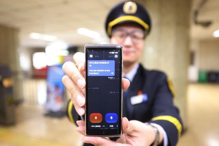 Nhân viên ga tàu điện ngầm ở Bắc Kinh sử dụng thiết bị phiên dịch để hỗ trợ hành khách nước ngoài. Ảnh: VCG.