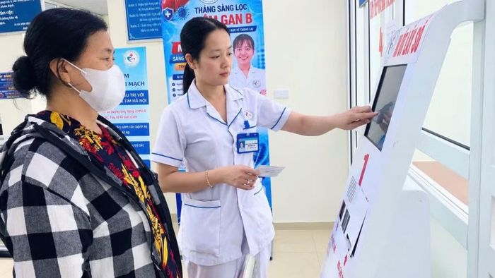 Cán bộ y tế hướng dẫn người dân bốc số đăng ký khám, chữa bệnh tại các bệnh viện tuyến dưới trên địa bàn. (Ảnh: THẮNG ĐẠT)