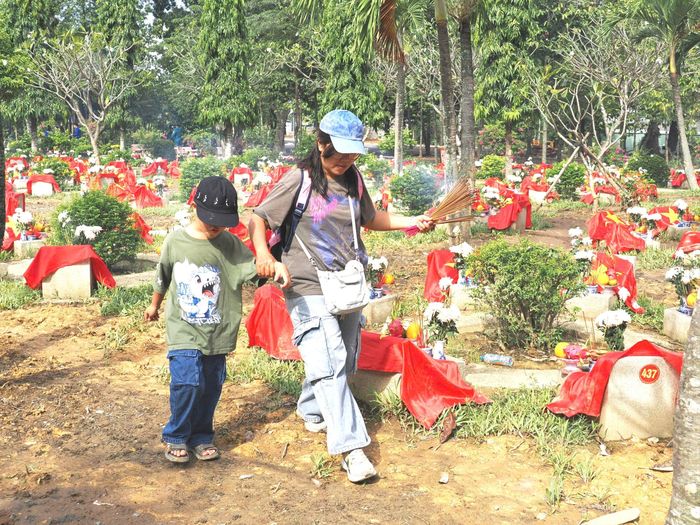 Nhiều gia đình đưa con nhỏ đến nghĩa trang thắp hương. Ảnh: HOÀNG HÙNG
