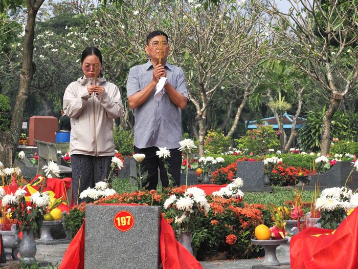 Ông Hồ Văn Lộc cùng con gái thắp hương tại các phần mộ liệt sĩ. Ảnh: HOÀNG HÙNG