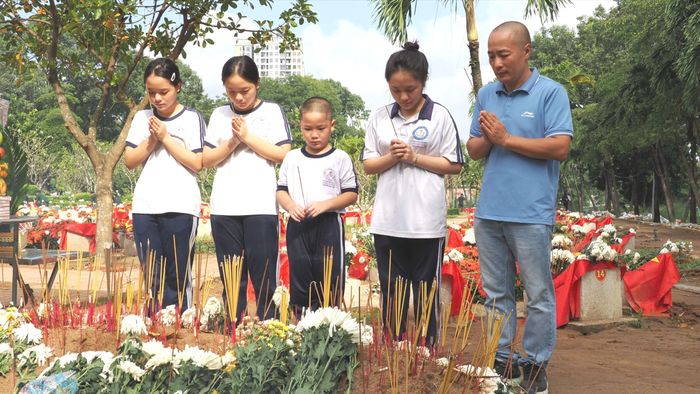 Ông Đào Duy Minh đưa 4 người con đến thắp hương tại các phần mộ liệt sĩ vừa được an táng. Ảnh: HOÀNG HÙNG