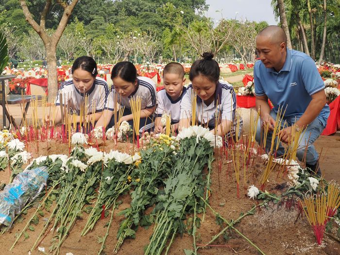 Ông Minh và các con thắp hương tại phần mộ tập thể 33 liệt sĩ. Ảnh: HOÀNG HÙNG