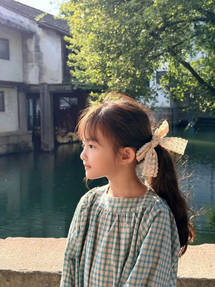 Trong loạt ảnh được chia sẻ, Winnie gây ấn tượng với mái tóc xoăn dày hơi xù tự nhiên, kết hợp cùng kiểu mái bằng ngộ nghĩnh. Phần tóc được buộc gọn lệch sang một bên, điểm xuyết chiếc nơ trắng xinh xắn. Cách tạo kiểu vừa điệu đà vừa phù hợp với lứa tuổi giúp cô bé trông như một nàng thơ nhỏ bước ra từ những trang truyện cổ tích. Ảnh: FB Winnie Hannie