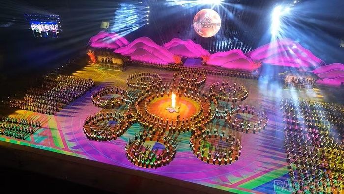 Các vòng người cuộn thành những đường xoắn quanh ngọn lửa, gợi nét trang trí trên khăn Piêu của người Thái. Sự phối hợp giữa đội hình biểu diễn, hình chiếu mặt sân và ánh sáng nhiều lớp đưa hoa văn truyền thống thành hình ảnh chuyển động trên sân khấu. Ảnh: Báo Lào Cai.