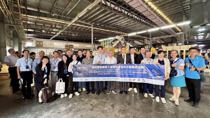 Các đại biểu và đại diện doanh nghiệp chụp ảnh lưu niệm tại khu vực ứng dụng công nghệ robot xếp pallet của nhà máy YFY Packaging (Ha Nam).