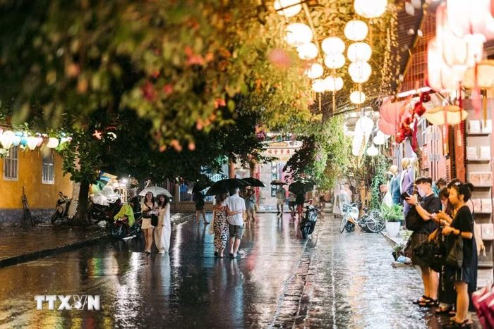 Ánh đèn lồng phản chiếu trên mặt đường ướt tạo nên một diện mạo khác của Hội An, ít rực rỡ theo cách của ngày nắng nhưng gần hơn với nhịp sống thường nhật của đô thị. (Ảnh: Phạm Tuấn Anh/TTXVN)