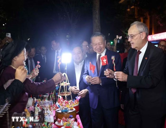 Tổng thống Thụy Sĩ Guy Parmelin bày tỏ sự thích thú với sản phẩm tò he của những nghệ nhân làng Xuân La - nét văn hóa dân gian Việt Nam độc đáo trên phố đi bộ hồ Hoàn Kiếm. (Ảnh: Thống Nhất/TTXVN)