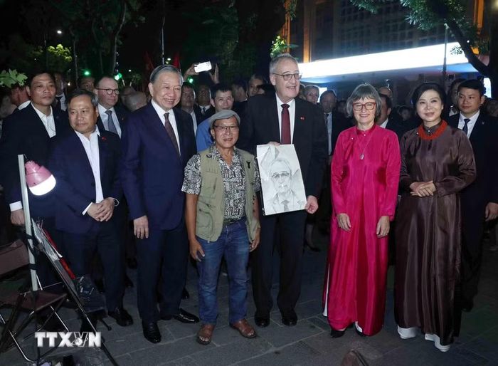 Một họa sỹ trên phố đi bộ tặng Tổng thống Thụy Sĩ Guy Parmelin bức ký hoạ chân dung Tổng thống. (Ảnh: Thống Nhất/TTXVN)