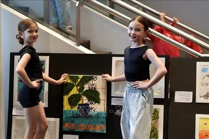 Hai em nhỏ cùng bức tranh yêu thích được trưng bày tại triển lãm. Ảnh: Lê Đạt/TTXVN