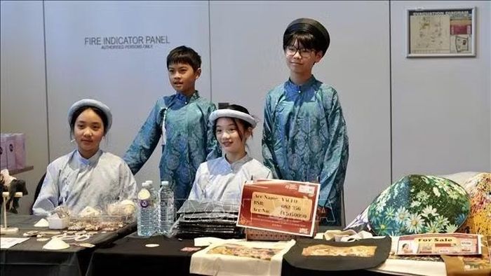 Các em nhỏ mặc áo dài tại quầy bán đồ lưu niệm để quyên góp cho chương trình. Ảnh: Lê Đạt/TTXVN